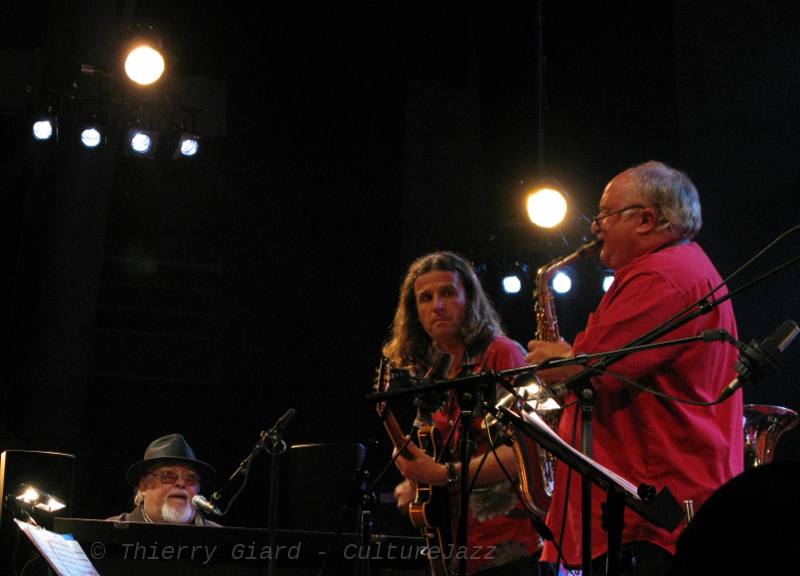 EddyLouiss_JMEcay_DHuck_29mai2011_w.jpg - Eddy chaloupe, Eddy swingue, Eddy biguine, Eddy fanfaronne, Eddy jazze, jobime et bossanove... Aux côtés de la horde de cuivres, des violoncelles annoncent le nouveau printemps du capitaine Nemo comme disait Nougaro.La fanfare du paradis du Père Eddy est portée par des solistes fidèles : Xavier Cobo ou Daniel Huck (ici, à l'alto) et Jean-Marie Ecay (guitare).C'était le dimanche 29 mai à Coutances : torride ! (T.G.)