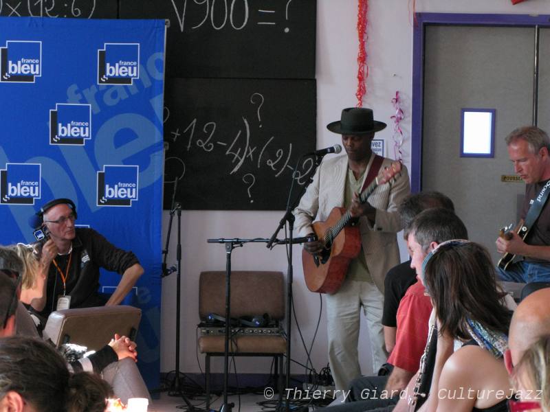 EricBibb_FranceBleu_29mai2011_w.jpg - Coiffé de son éternel chapeau, le guitariste-chanteur Eric Bibb aime se présenter comme un troubadour. Il n'hésite pas à jouer et chanter quand l'occasion se présente comme ici dans le "Bar des Filles" au théâtre de Coutances à l'invitation de France-Bleu ! (T.G.)