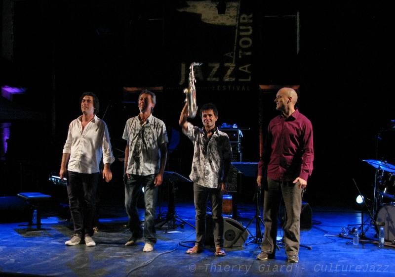 KARTET_salutFinal_JALT_14aout2012_05.JPG - Kartet, sur la scène de Jazz à La Tour le 14 août. Cette formation possède une solide réputation dans le paysage du jazz moderne façais depuis deux décennies. Benoît Delbecq (piano), Hubert Dupont (contrebasse) et Guillaume Orti (saxophones alto et soprano) sont unis par une même envie de faire avancer le jazz en repensant les codes et les modes de jeu du quartet sans tourner le dos à la tradition. Dommage que le quatrième homme ait été absent ce soir-là : Chander Sardjoe était remplacé à la batterie par Stéphane Galland, instrumentiste très doué qui a suivi les partitions sans défaillir mais sans pouvoir vraiment s'exprimer...