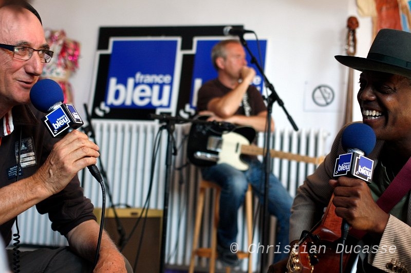 09-Dubourg_Bibb_Jslp11_byDucasse.jpg - Autre figure de l'odyssée de Jazz sous les Pommiers avec André Levauffre, celle de Michel Dubourg. Homme de radio également militant, sans qui la scène caennaise serait moins fastueuse. Toujours en pointe, il reçoit  en direct le bluesman Eric Bibb. Dimanche 29 mai 2011, foyer du théâtre.